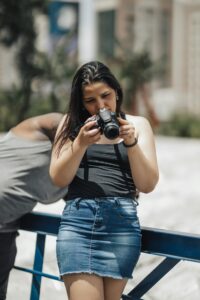 A young woman reviewing photos on her camera, enjoying a summer day outdoors.