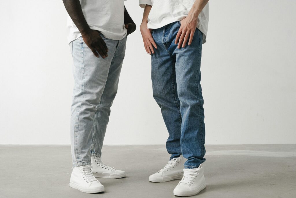 Close-up of two individuals wearing jeans and white sneakers in a minimalist setting.